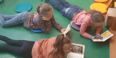 Powiększ grafikę: Cztery dziewczynki leżą na dywanie i czytają książki.
