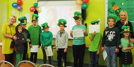 Powiększ grafikę: Obraz przedstawia uczniów i nauczycieli pozujących do zdjęcia w zielonych ubraniach i irlandzkich kapeluszach.