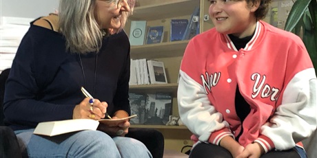 Powiększ grafikę: Na zdjęciu Roksana Jędrzejewska-Wróbel podpisuje książkę dziewczynce, która siedzi obok niej.